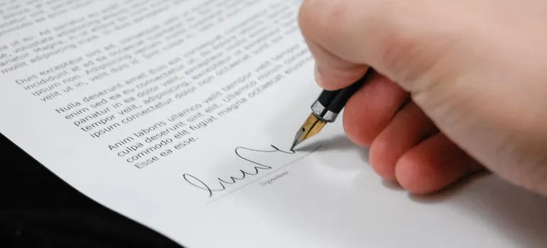a hand signing a contract and avoiding mistakes when renting self storage