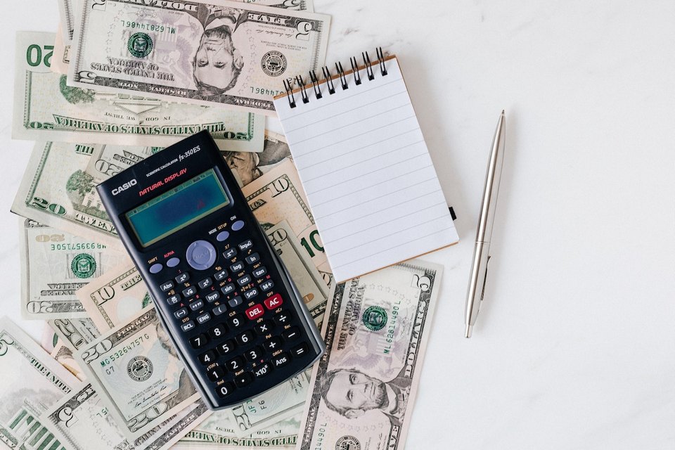 calculator money notebook pen on a table