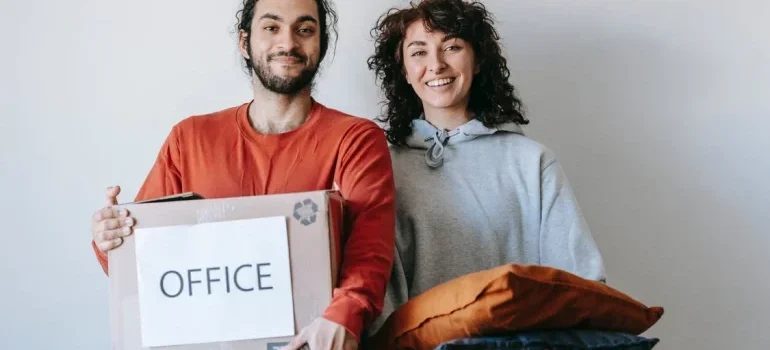 A couple with a box and items, relocating their office