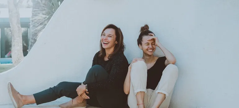 Two friends are sitting next to each other and laughing after moving back to Eagle after college.