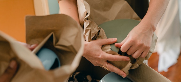 People packing plates into packing paper.