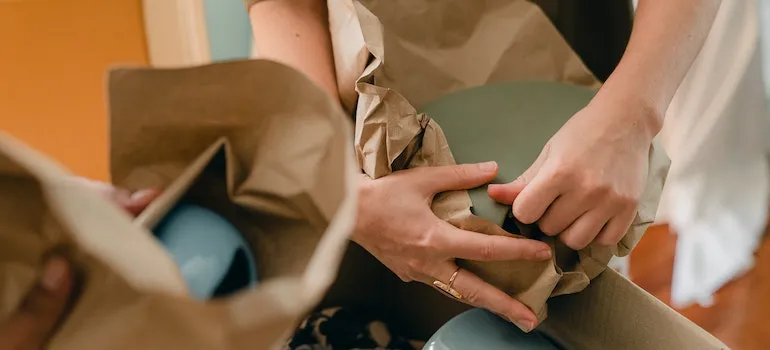 People packing plates into packing paper.