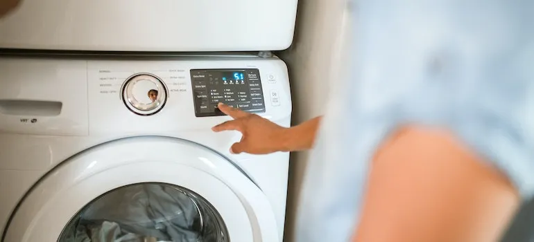 person using washing machine to prepare clothes for storing