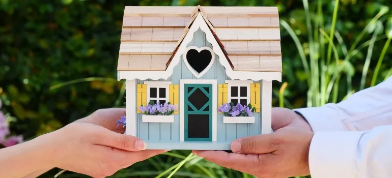 two people holding a cute house maquette