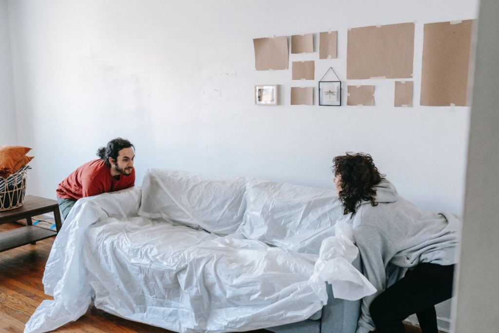 Two people carrying difficult pieces of furniture