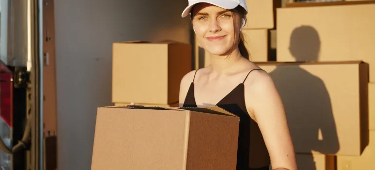 A woman smiling and carrying a box