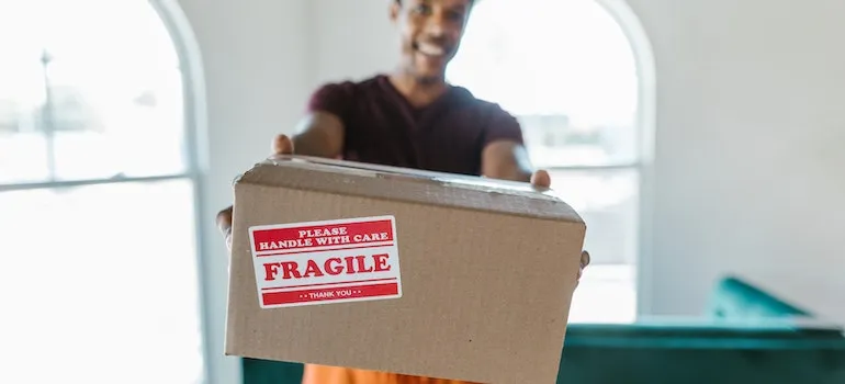 man holding a moving box and handing it over to movers Eagle ID