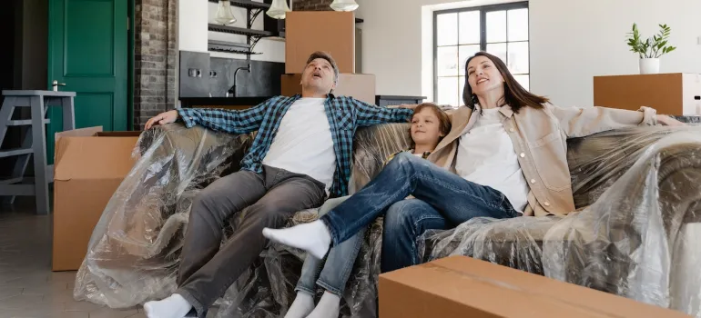 A family sitting on couch covered with plastic after renting pods when moving to Idaho