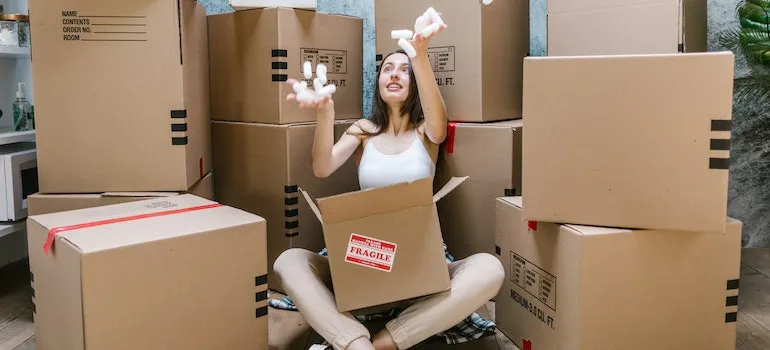 woman sitting in front of moving boxes and playing with packing peanuts