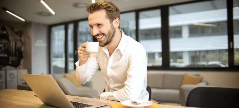 a man drinking coffee and researching reasons families decide to move on his laptop