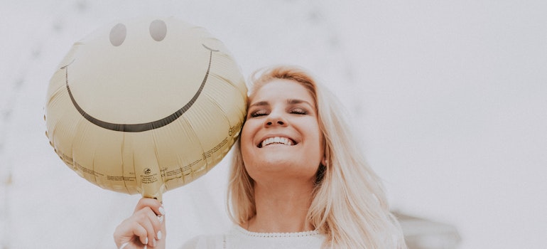 Woman smiling and holding a yellow balloon 