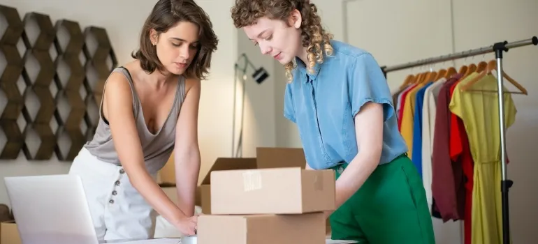 Two women packing clothing to start an online clothing store in Nampa