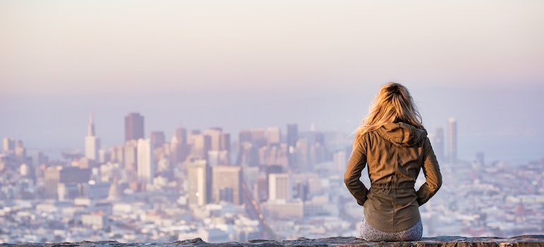 Woman overlooking the city skyline thinks can moving make you happier
