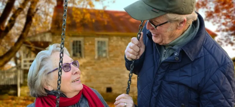 an old woman sitting on a wing and a man next to her talking