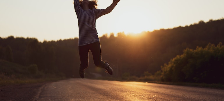 woman happily jumping after reading the article Can moving make you happier