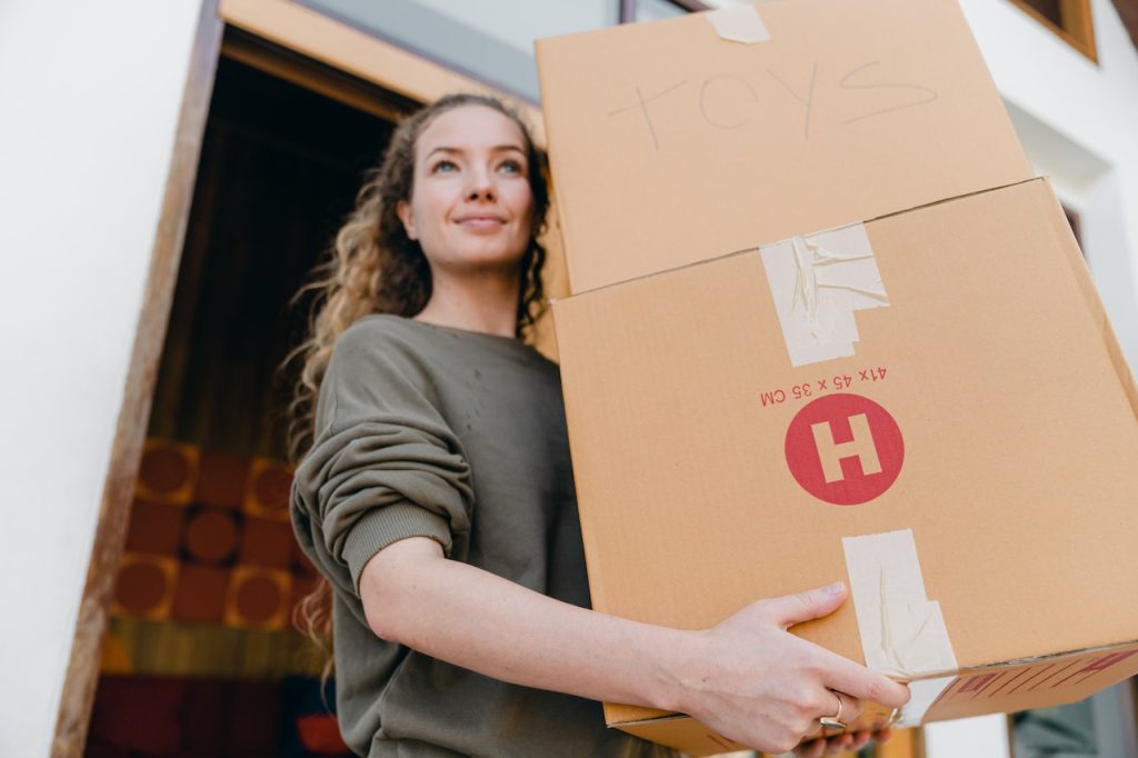 Young woman with boxes while moving to one of Boise storage facility options