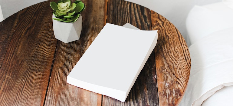 a white book and a succulent on a wooden table