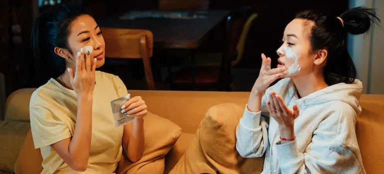 two women sitting on a couch doing face masks trying co-living vs roommates option