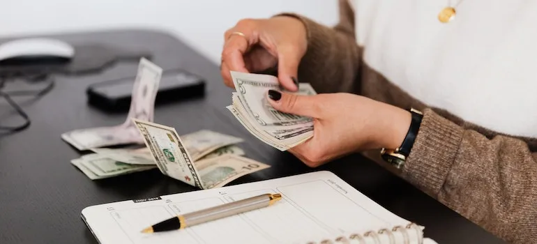 a woman counting money considering co-living vs roommates arrangement