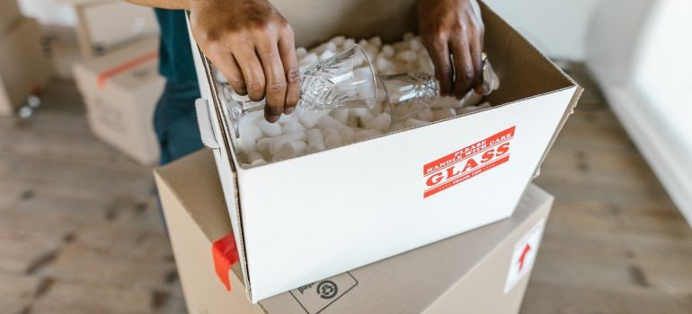 a man packing glasses inside a box