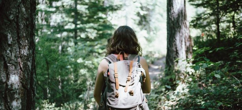 A woman hiking through woods with a backpack following a hiker's guide to the Boise Area