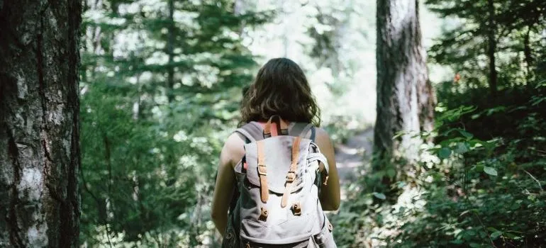 A woman hiking through woods with a backpack following a hiker's guide to the Boise Area