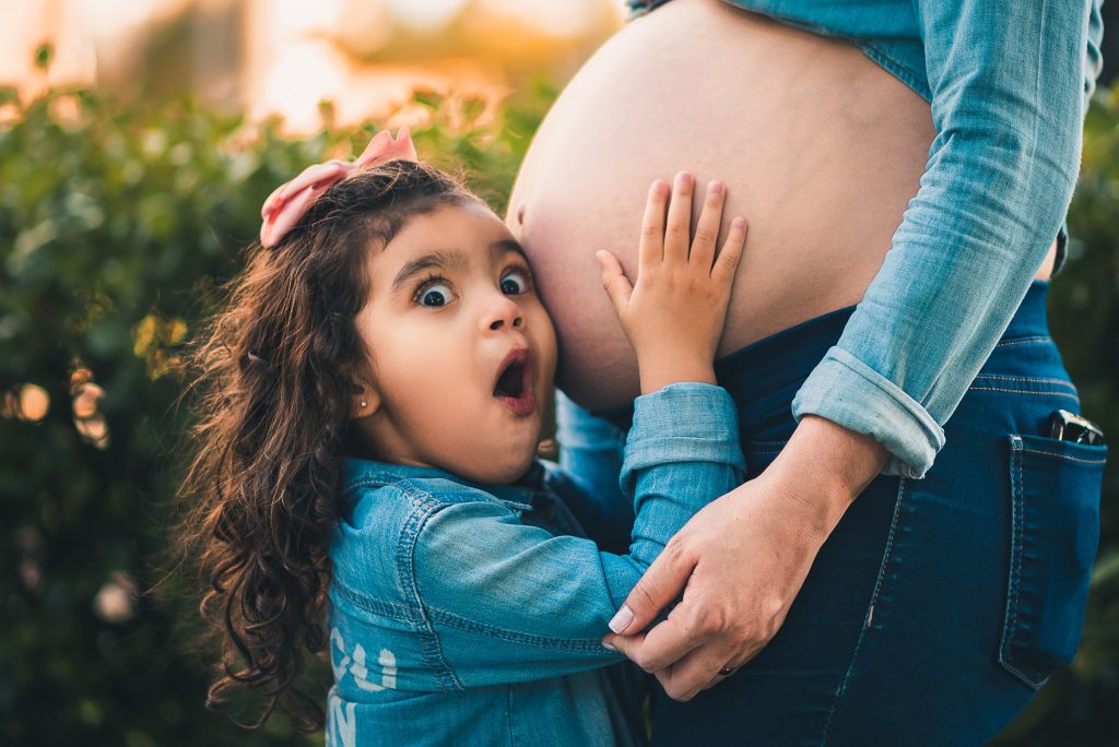 Girl listening to her mom's pregnant belly