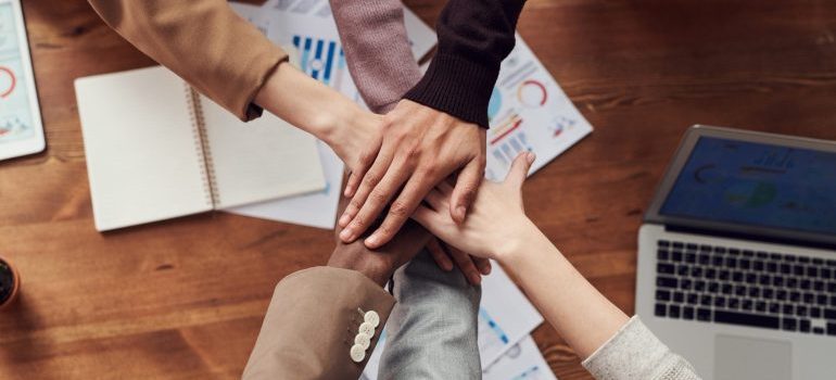 Team putting hands together in an office after using mobile storage for commercial purposes