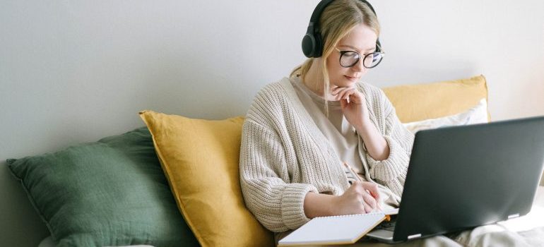 Woman with headphones and laptop taking notes about relocating overseas from Idaho