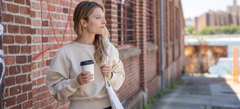 Woman on the street holding coffee and looking at the city