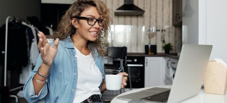 A woman drinking coffee on a video call after relocating overseas from Idaho
