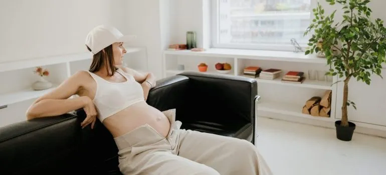 A pregnant woman sitting on the couch and plans to move your home in Boise while pregnant