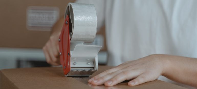 A person taping a moving box