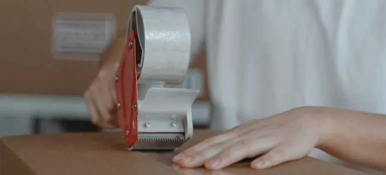 A person taping a moving box