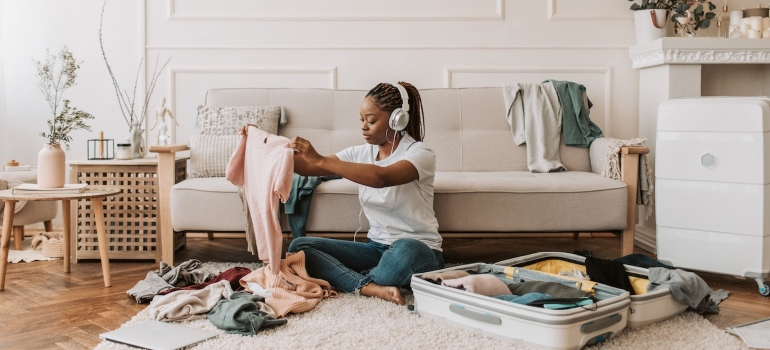 woman with earphones packing clothes shows how to handle packing your Boise home for a move