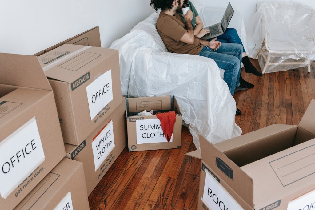 A couple sitting next to a stack of labeled boxes looking into the do's and don'ts of storing items in a storage unit