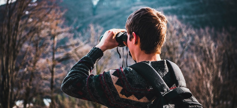 a man holding binoculars to see neighborhoods and attractions in the Boise area