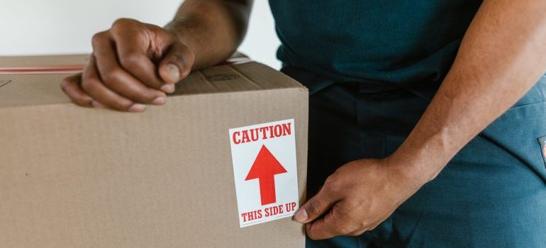 Man holding a box with a caution sign