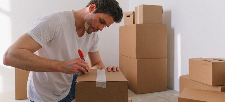 A man writing on a box according to do's and don'ts of storing items in a storage unit