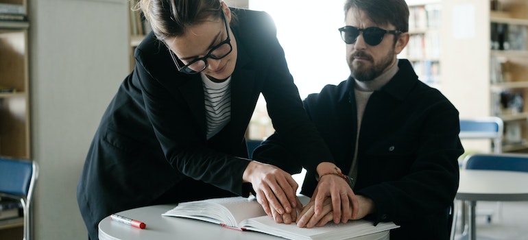 a woman helping a man read braille