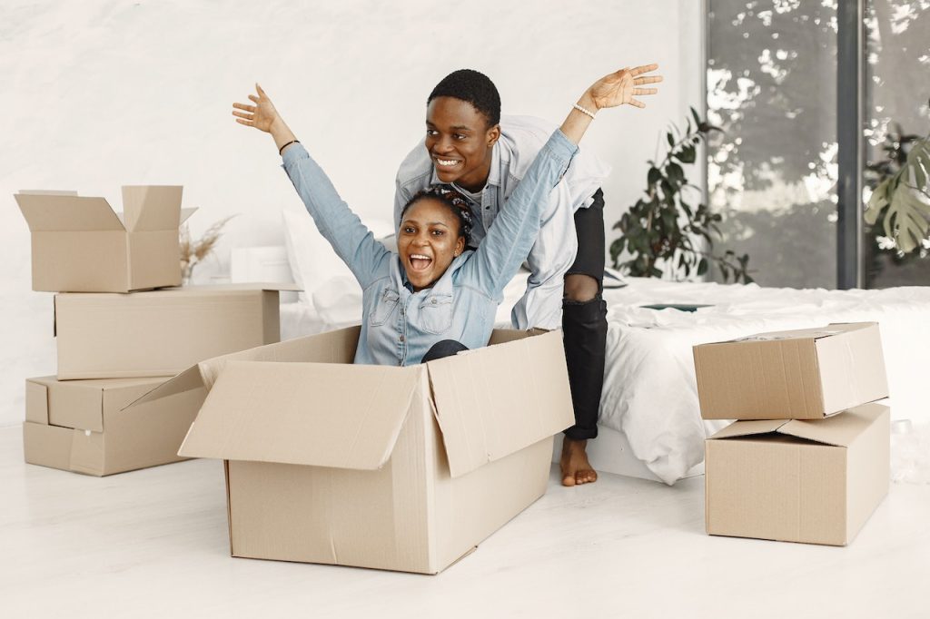 A Man Pushing a Happy Woman Sitting in a Cardboard Box