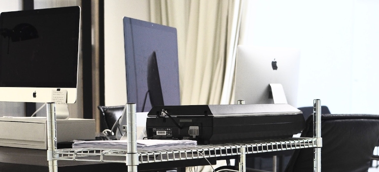 Metal shelves with printer, PCs and plastic boxes in office