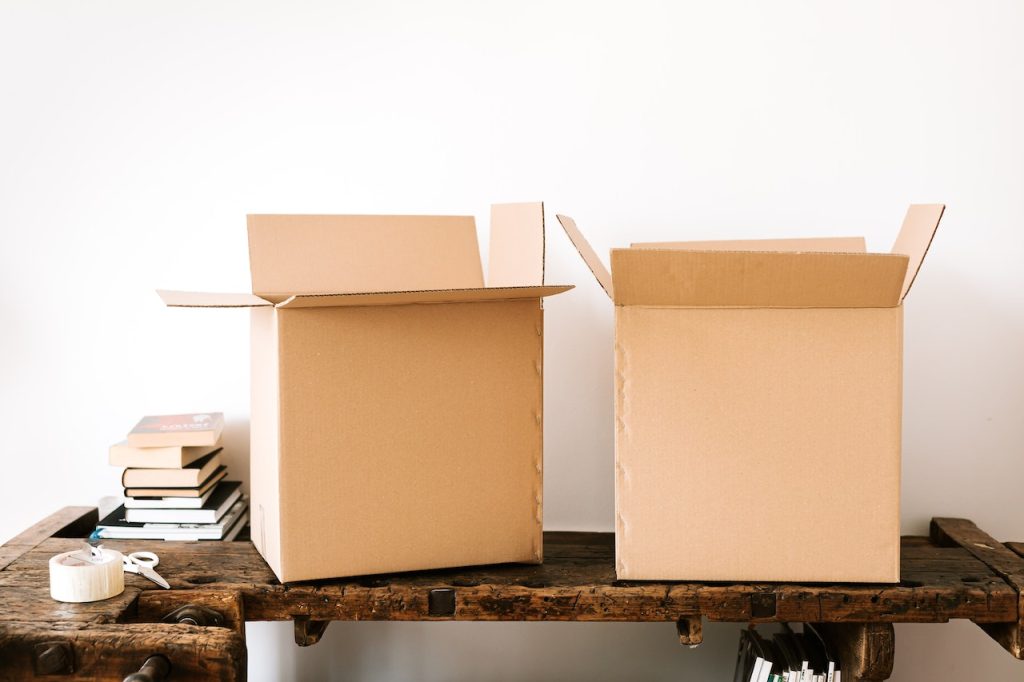 Carton boxes and stacked books on table during unpacking after the Meridian move