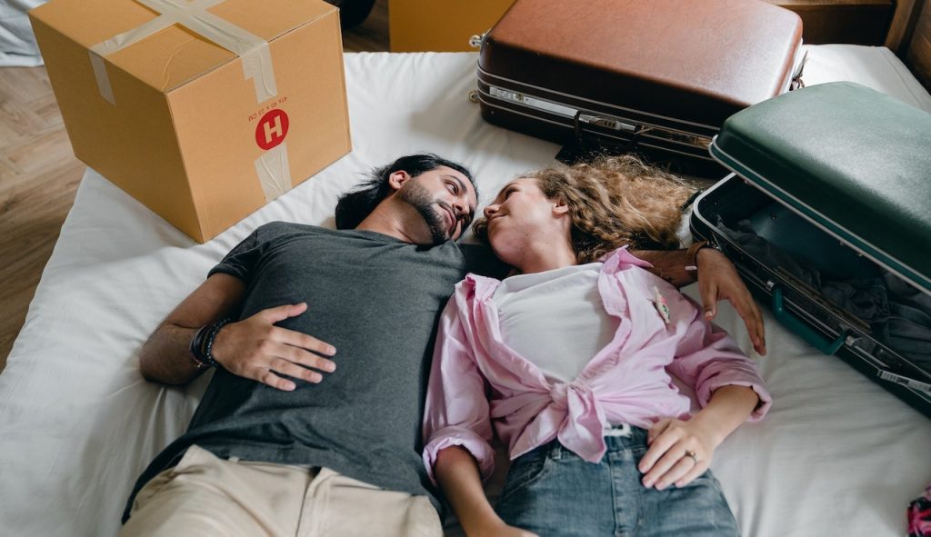 A couple smiling on a bed is overcoming post-move fatigue in Idaho