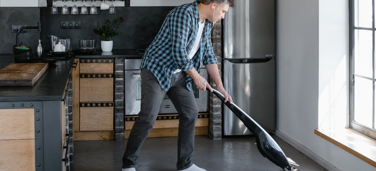 A man in plaid long sleeves vacuuming the floor