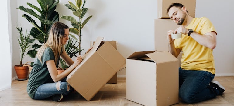 Content couple packing belongings into cardboard boxes
