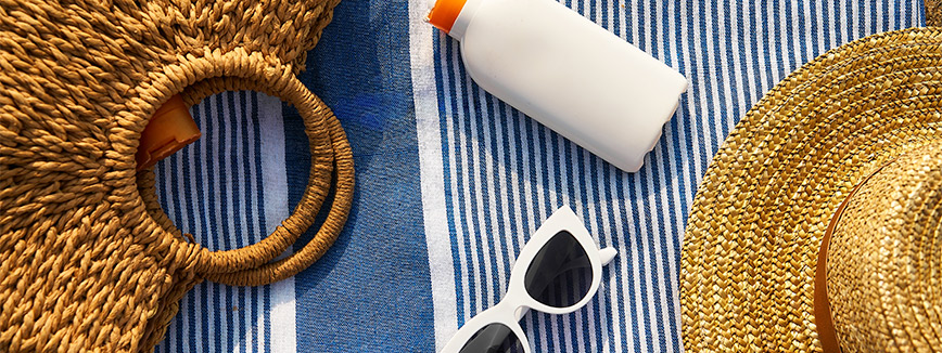 beach things: sunglasses, sunscreen, hat and purse. 