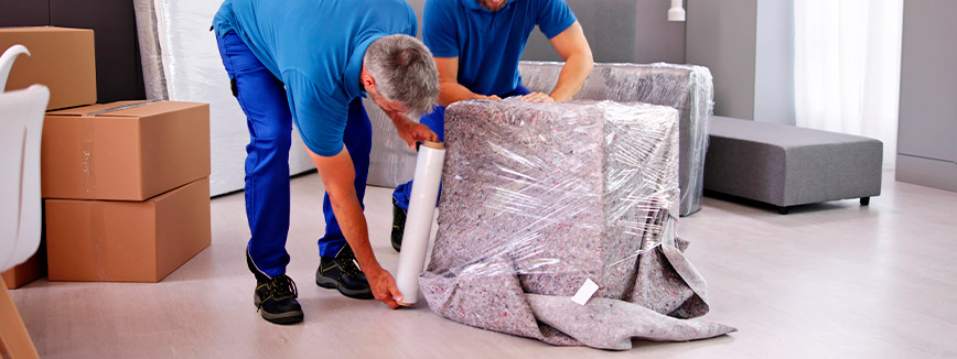 Two men in blue shirts unpack a large piece of furniture, showcasing local moving services in Boise, Idaho.