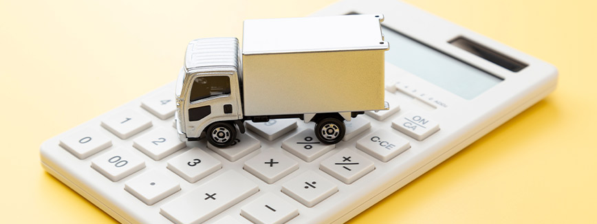 A white calculator topped with a toy truck, representing Peasley Movers' guide to local moving services in Boise, Idaho.