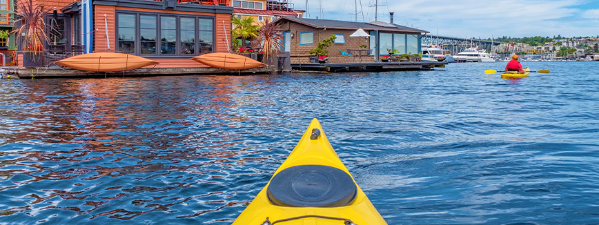  A kayak rests in the water near a house, representing the scenic lifestyle awaiting those relocating from Boise to Seattle.